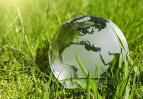 Motiv: Eine gläserne Weltkugel liegt im grünen Gras. (Foto: Stockwerk-Fotodesign - Fotolia.com)