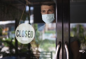 Motiv: Ein Mann mit Mund-Nasen-Schutz steht hinter der geschlossenen Tür eines Restaurants. (Foto: Irina - stock.adobe.com)