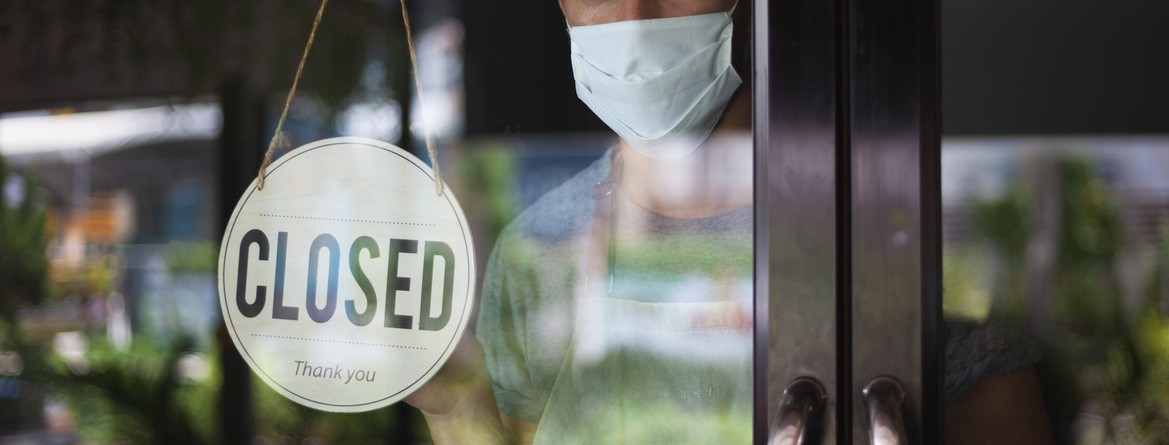 Motiv: Ein Mann mit Mund-Nasen-Schutz steht hinter der geschlossenen Tür eines Restaurants. (Foto: Irina - stock.adobe.com)