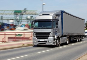 Motiv: Ein Lastwagen fährt auf der Autobahn. Im Hintergrund ist ein Containerhafen (Foto: fotofuerst - Fotolia.com)