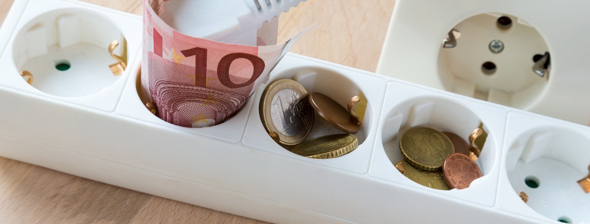 Motiv: In einer Steckerleiste liegen Geldstücke und ein 10 Euro Schein (Foto: hugin1 - Fotolia.com)
